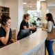 Busy eye care practice front desk with staff answering phones, checking in a patient, and sorting eyewear frames